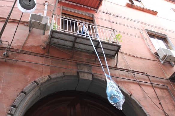 Imagen de una mujer subiendo la compra con una cuerda por el balcón